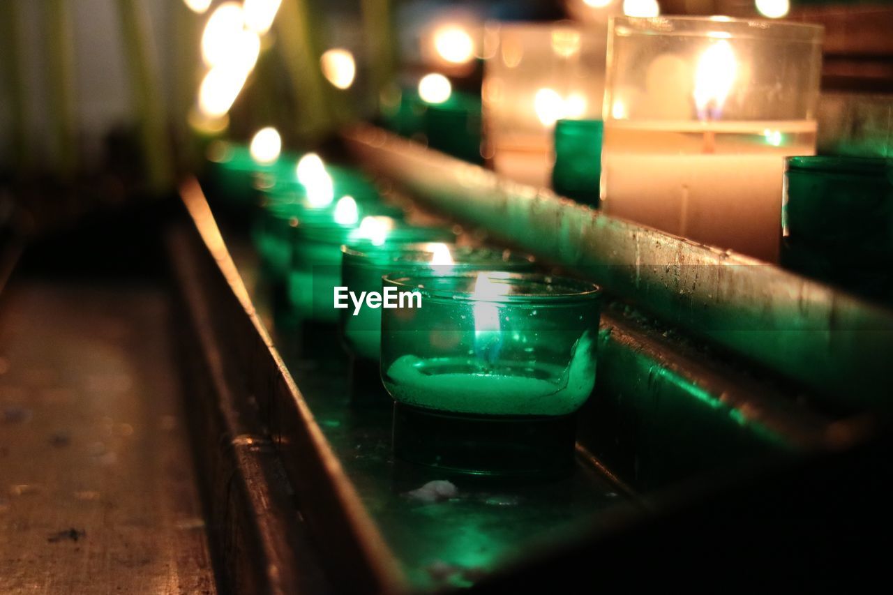 CLOSE-UP OF LIT CANDLES IN ROW