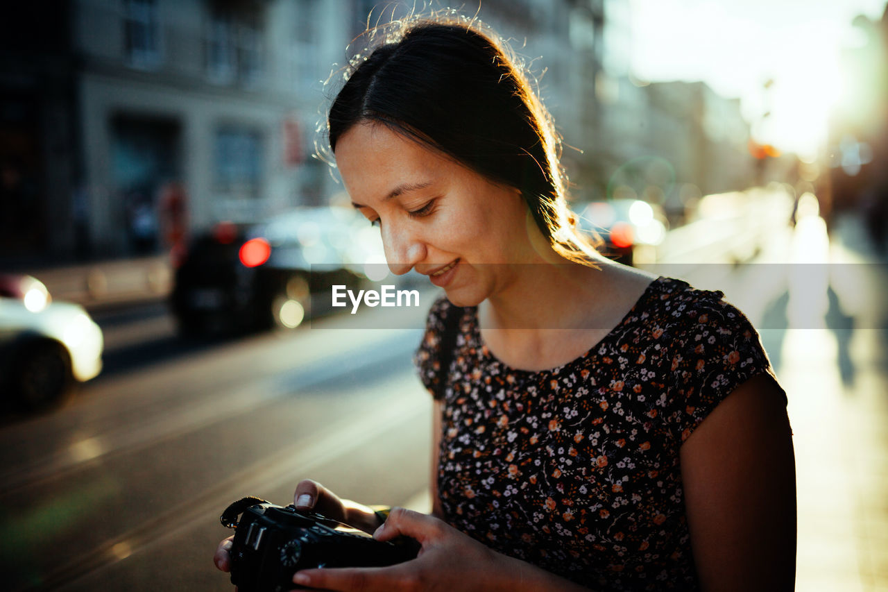 Mid adult woman photographing while standing on road in city