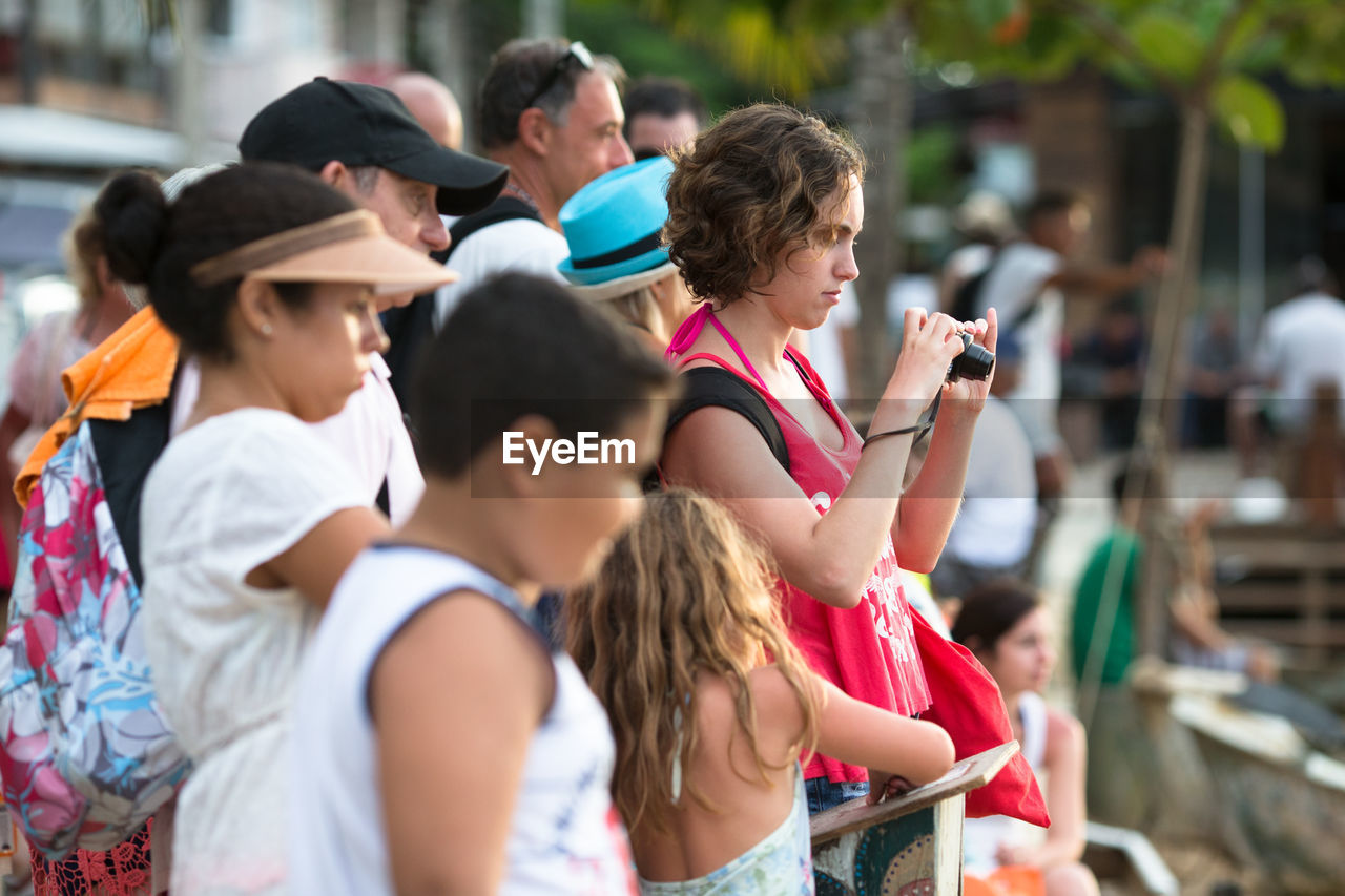 GROUP OF PEOPLE PHOTOGRAPHING FRIENDS ON MOBILE PHONE