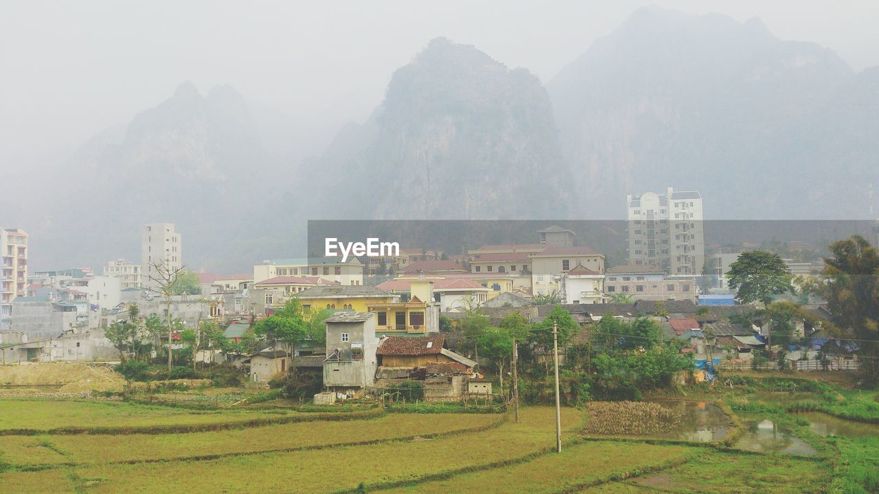 View of townscape by mountains in foggy weather