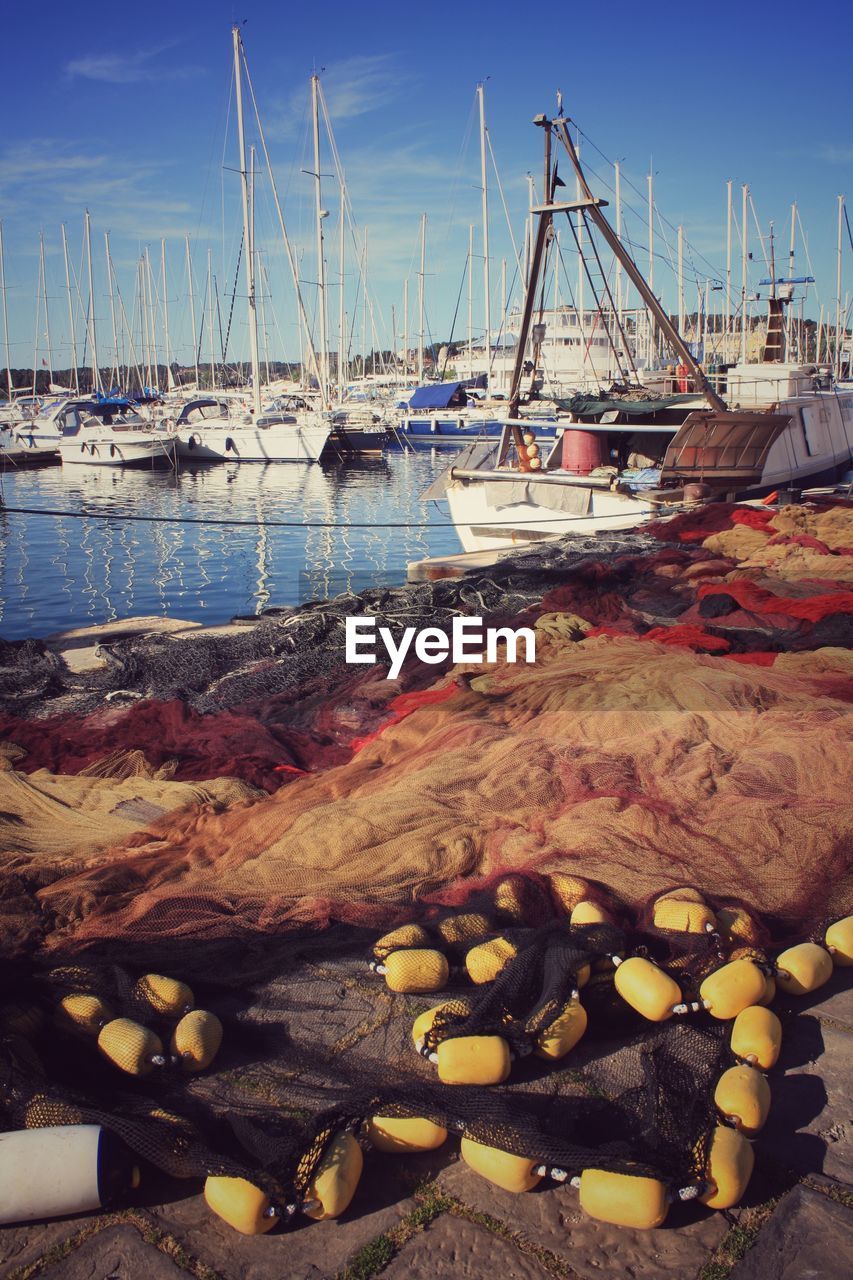 Sailboats moored at harbor and close up of nets