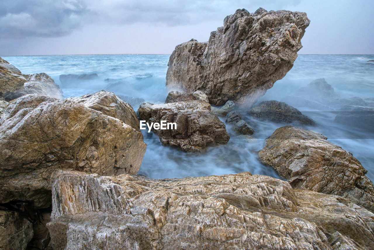 Scenic view of rocks in sea against sky