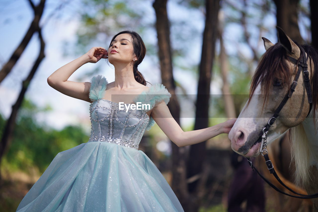 Portrait of a beautiful woman with a horse in the forest background.