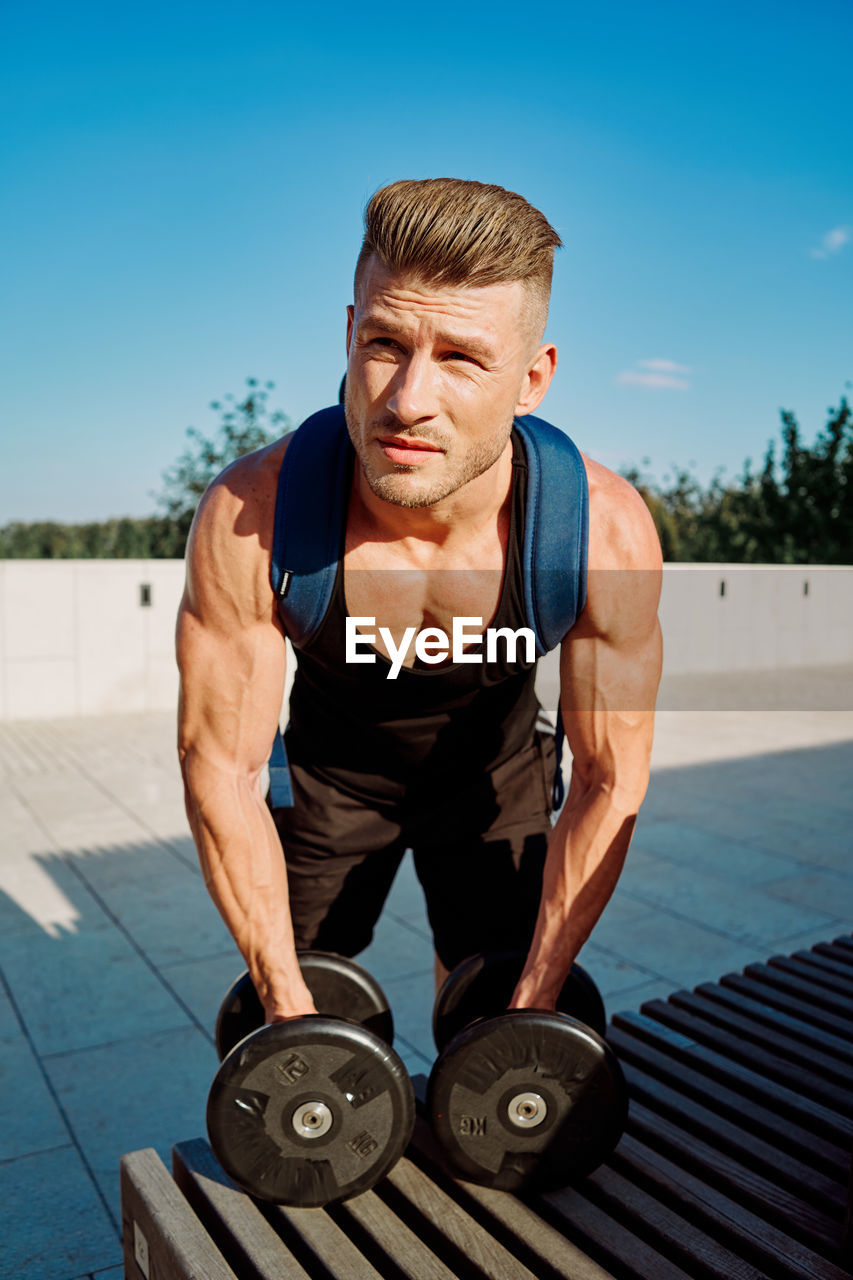 portrait of smiling young man exercising in gym