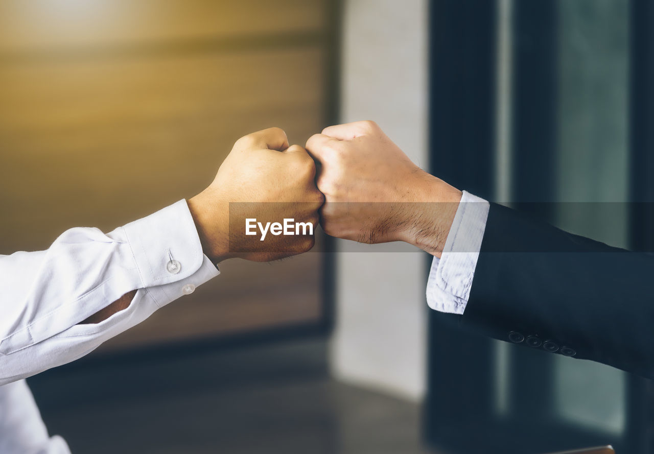 Cropped image of businessmen bumping fist at office