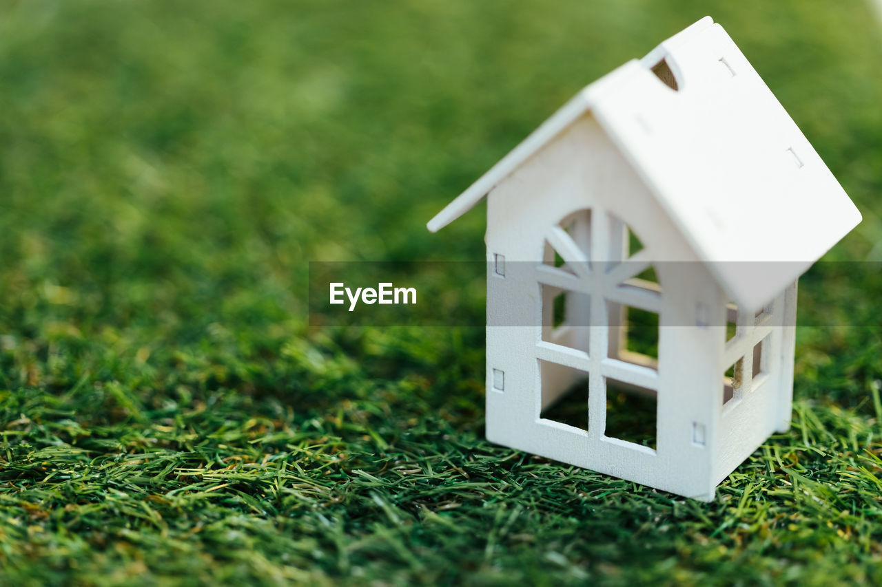 CLOSE-UP OF BIRDHOUSE ON GREEN FIELD