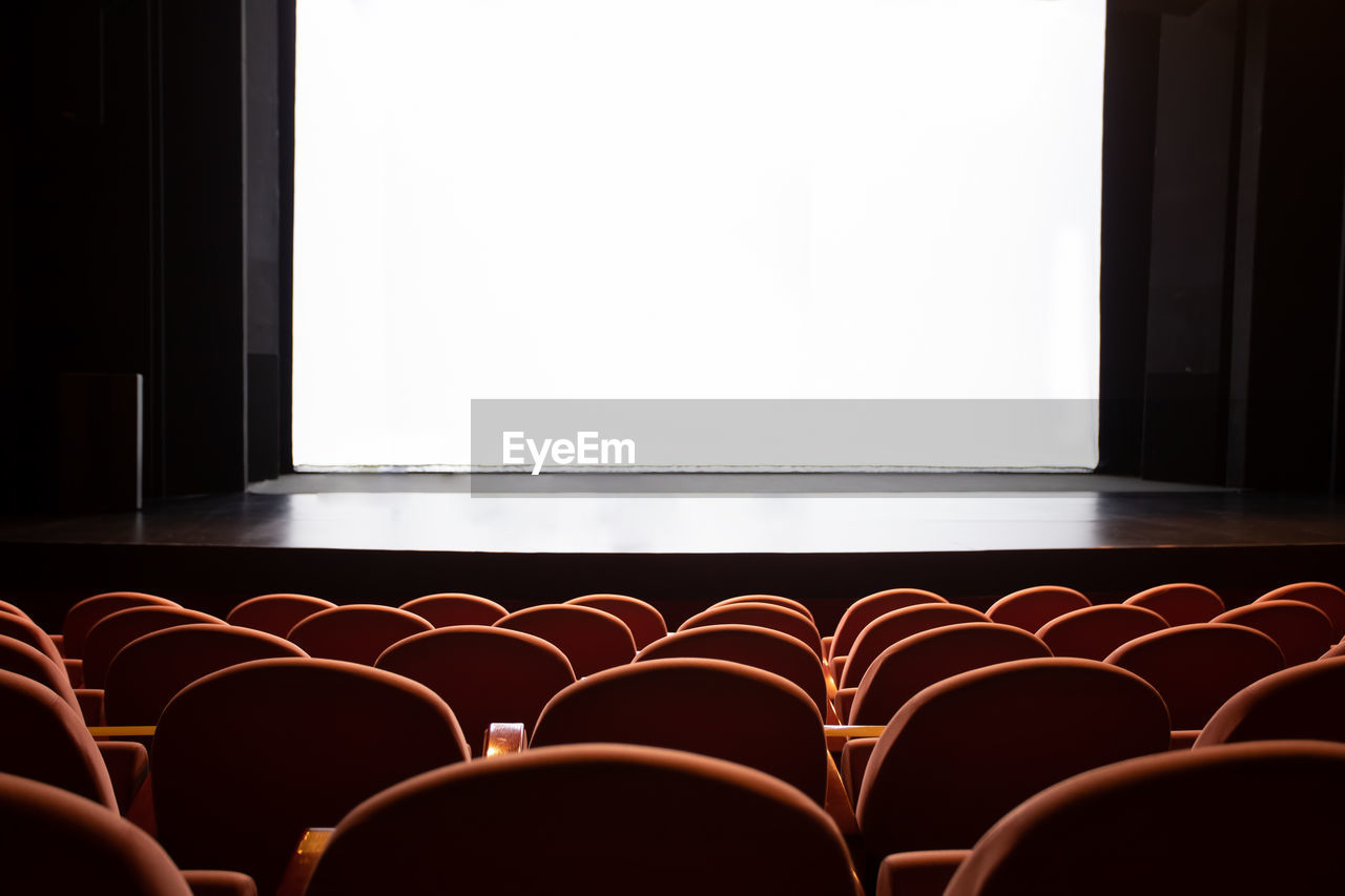 seat, indoors, arts culture and entertainment, movie theater, chair, auditorium, empty, in a row, copy space, no people, stage theater, film industry, absence, projection screen, stage, lighting, movie, theatre, conference hall