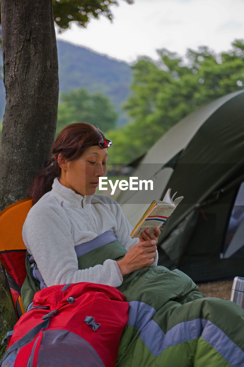 Woman reading a book at campsite