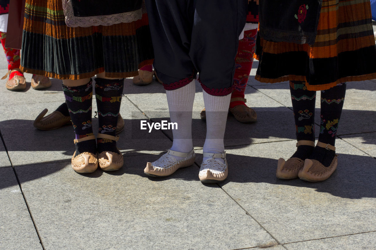 Low section of people in traditional clothing standing on footpath