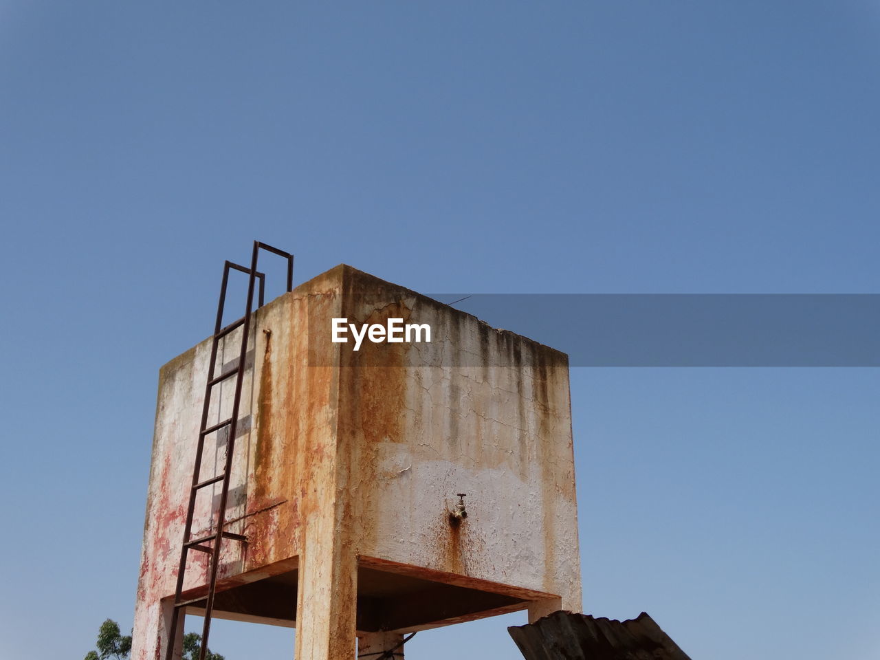 LOW ANGLE VIEW OF RUSTY ABANDONED BUILDING AGAINST CLEAR SKY