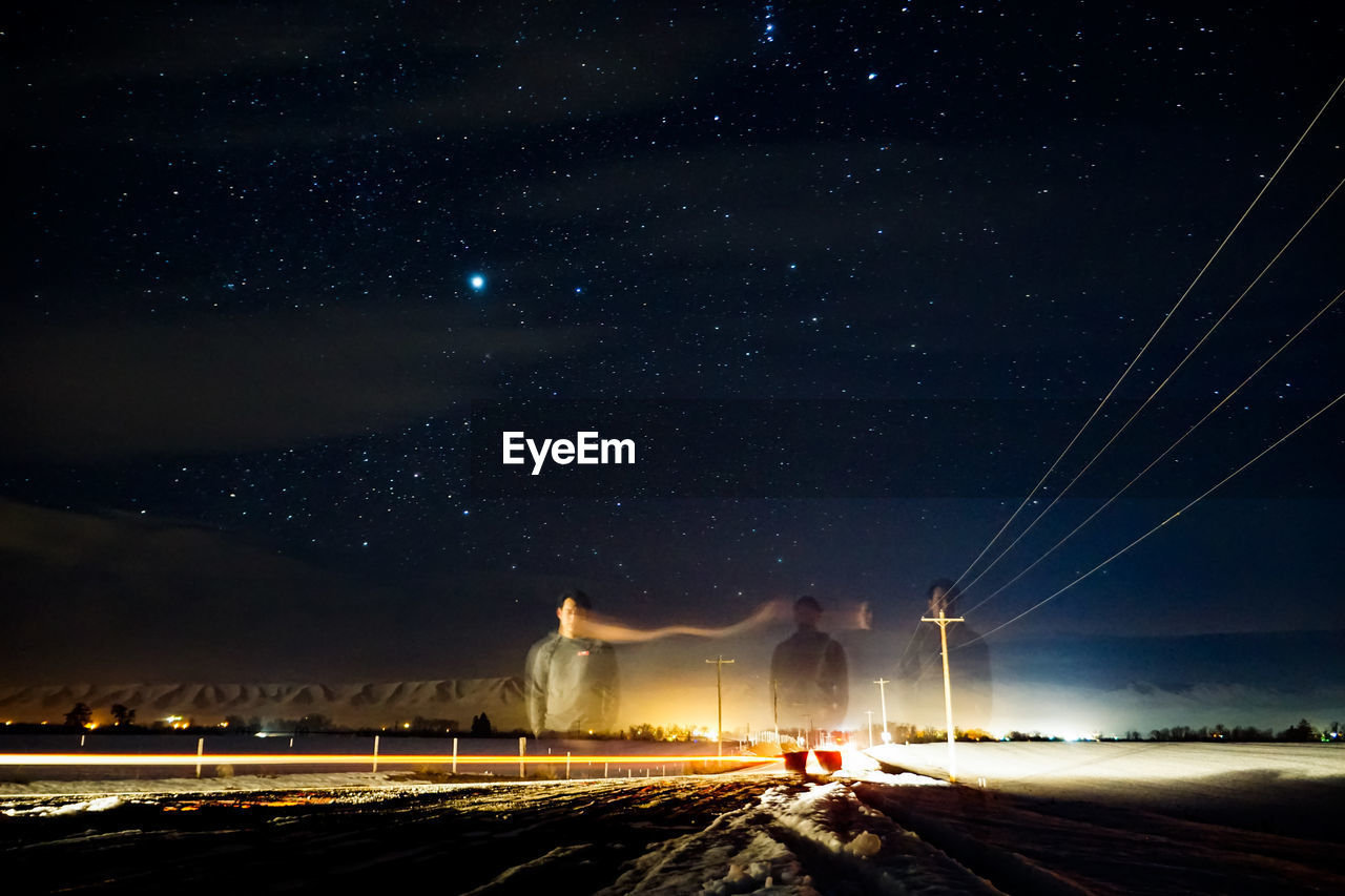 Multiple exposure image of man standing on street against star field at night