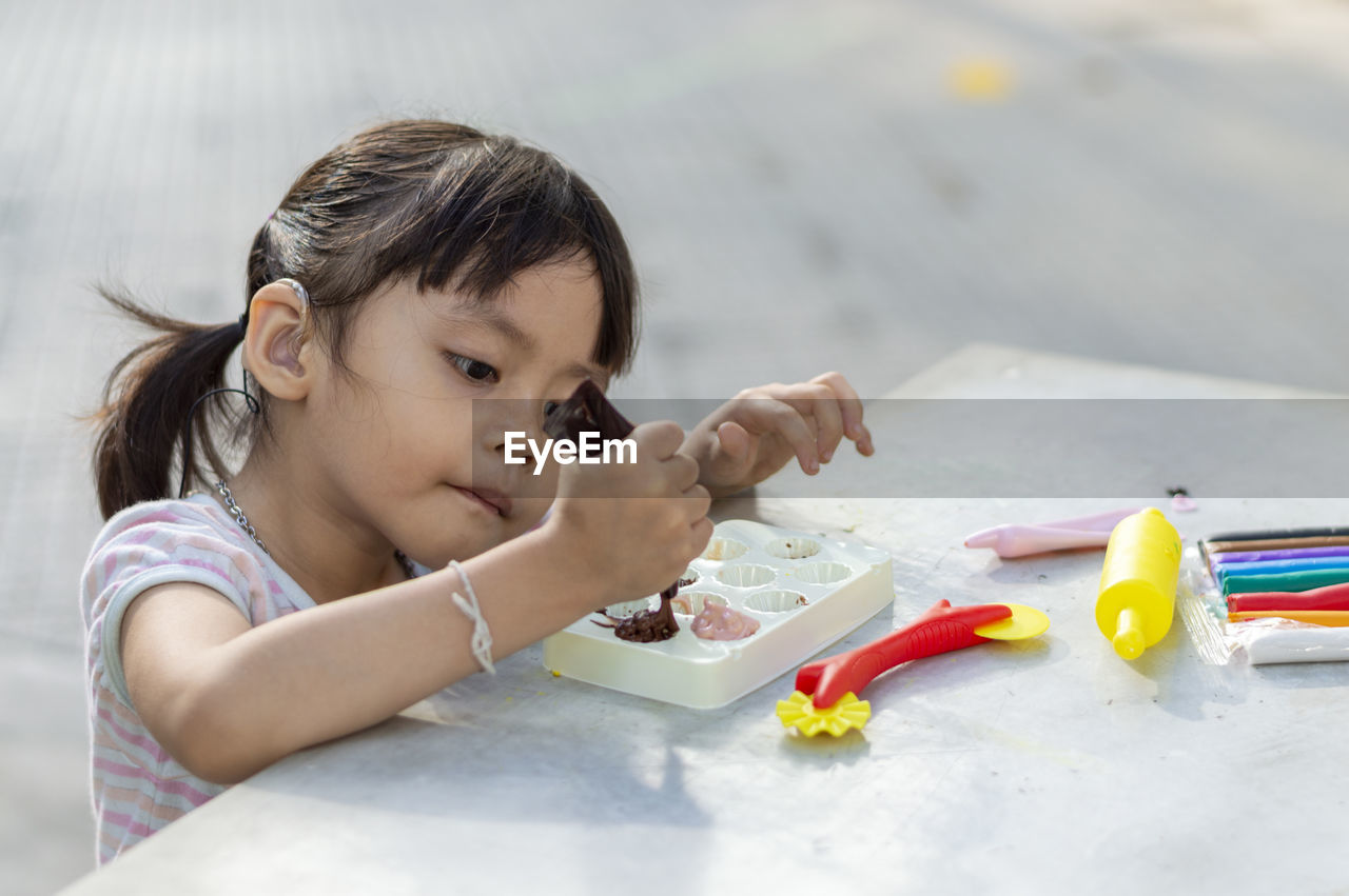 Close-up of cute girl playing with childs play clay at table outdoors