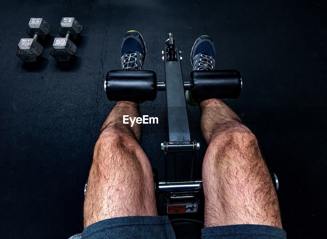 Low section of man lifting weights at gym