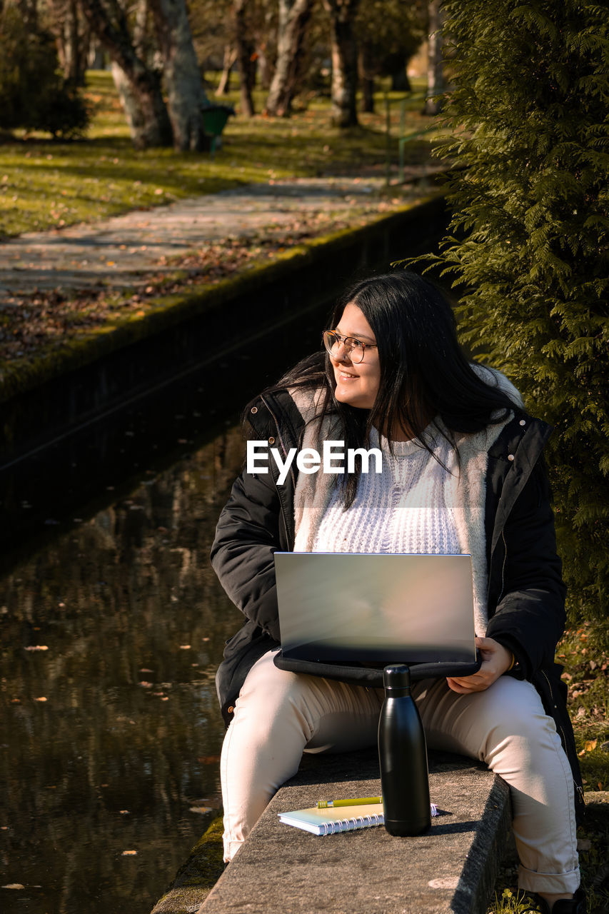 Woman working in the park with laptop. teleworking outdoors due to coronavirus. online business.