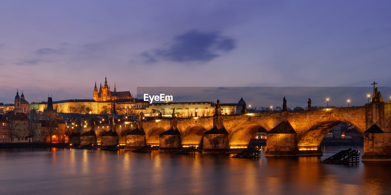 Bridge over river in city at dusk