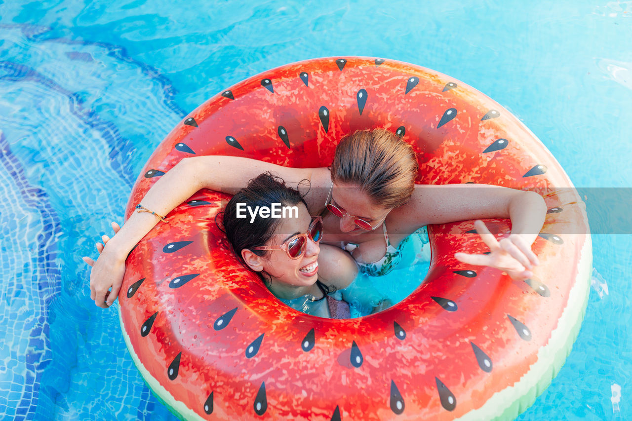 HIGH ANGLE VIEW OF A WOMAN LYING ON SWIMMING POOL