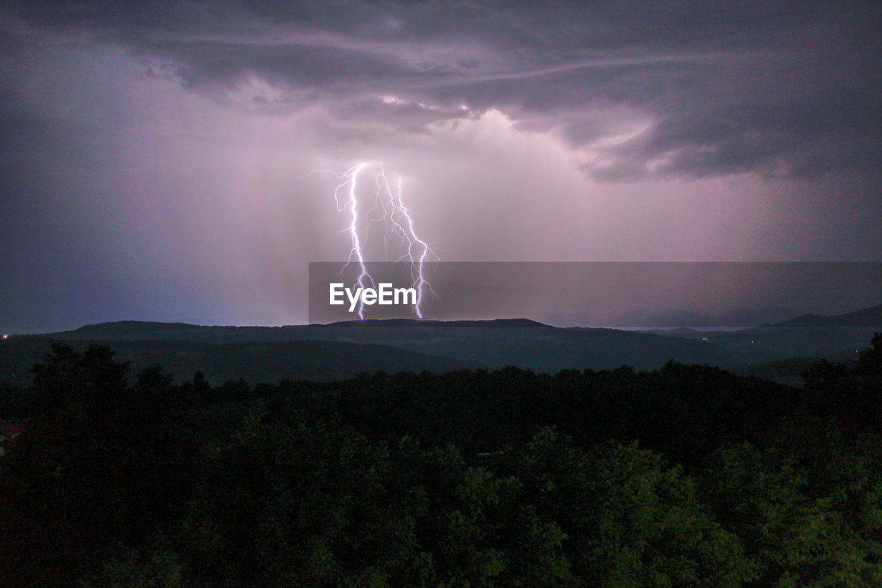 Lightning over landscape against storm clouds