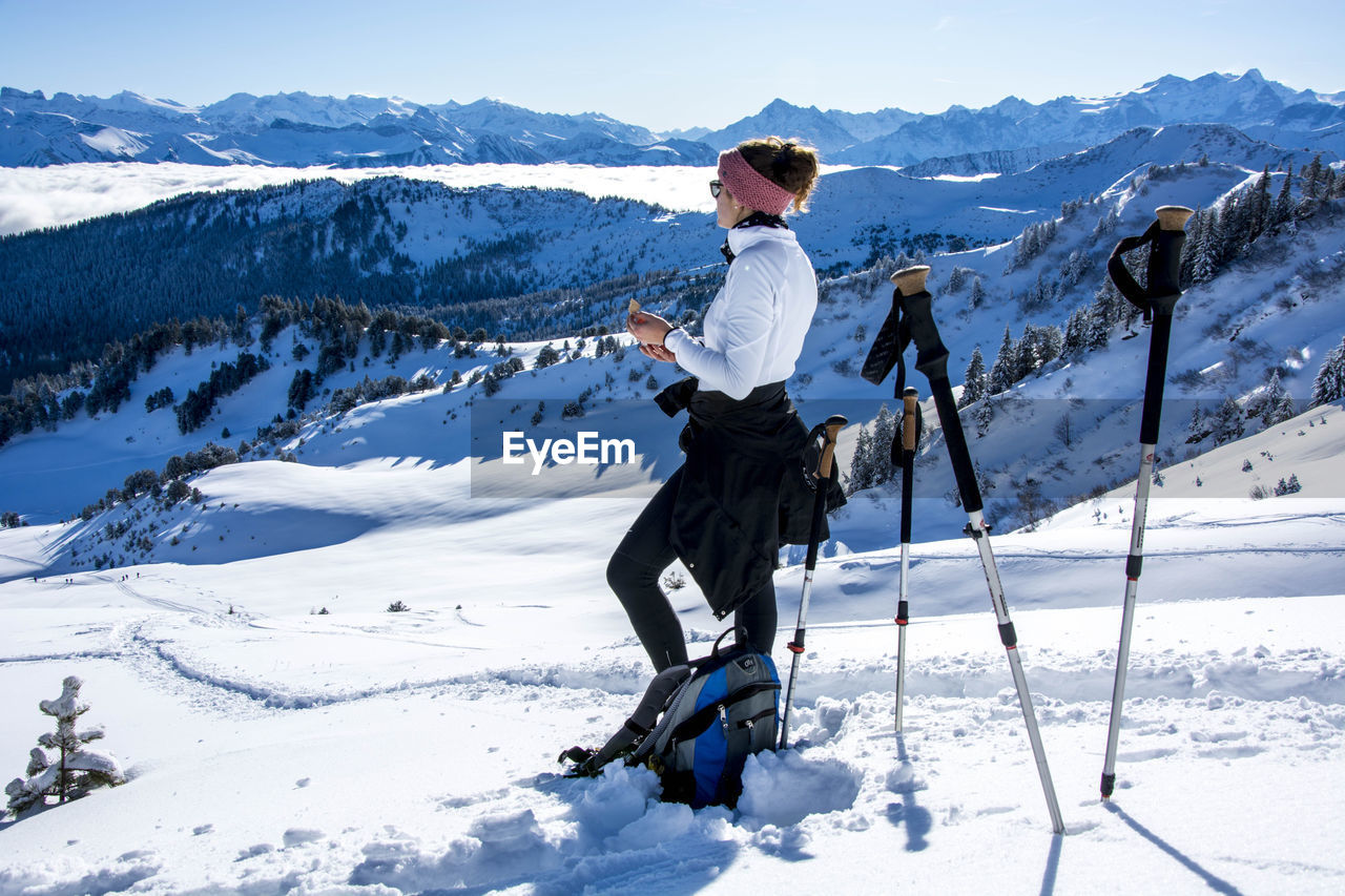 FULL LENGTH OF MAN STANDING ON SNOWCAPPED MOUNTAINS