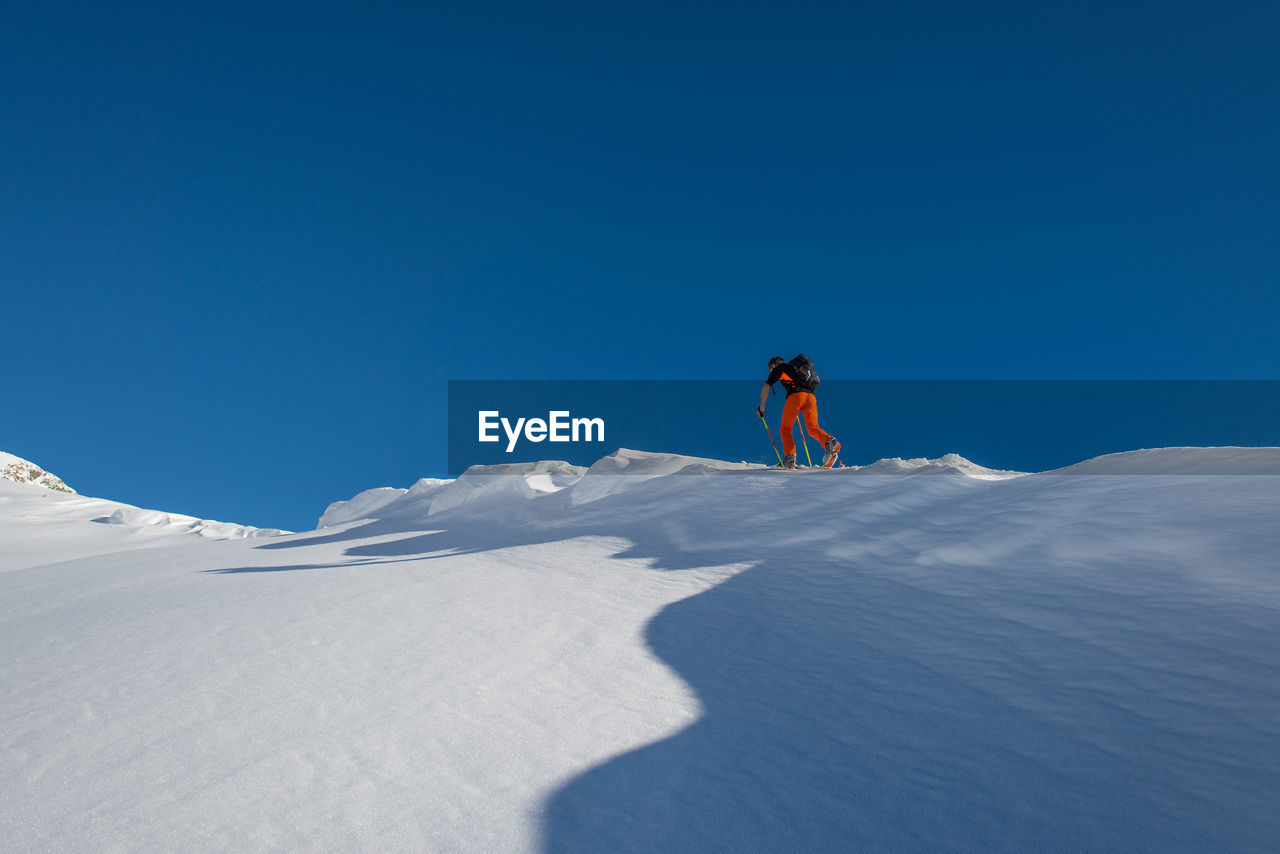 PERSON ON SNOW COVERED MOUNTAIN AGAINST BLUE SKY