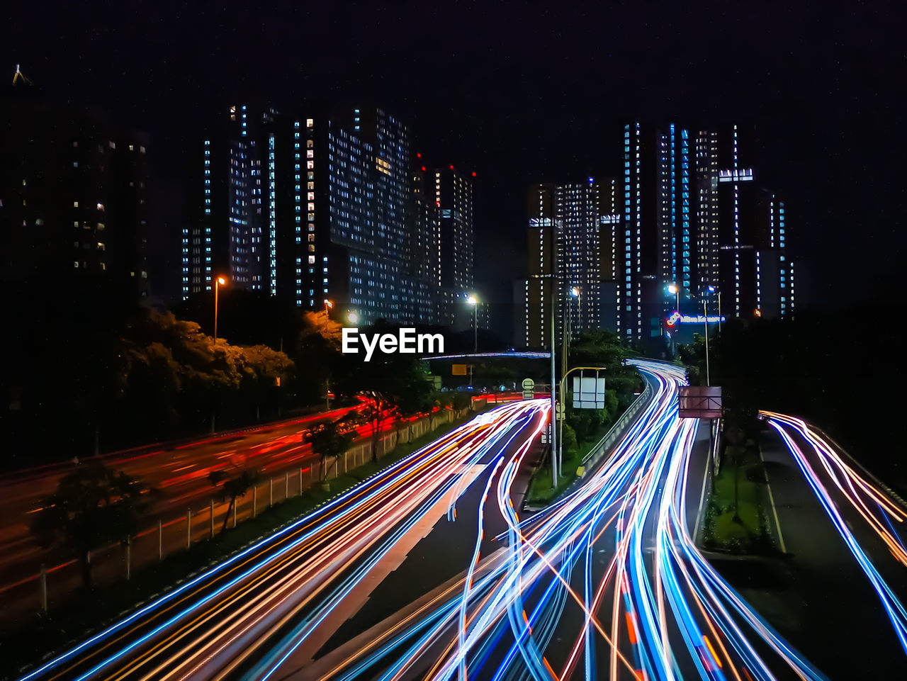 Light trails on city street by buildings at night