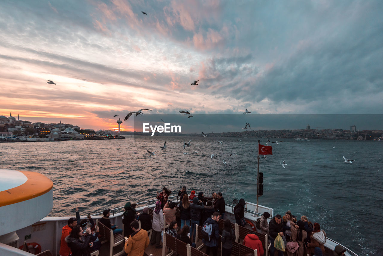 GROUP OF PEOPLE IN SEA AGAINST SKY