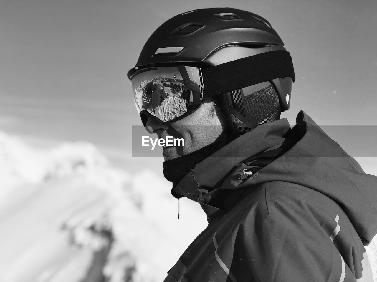 Side view of smiling mature man wearing ski helmet against sky