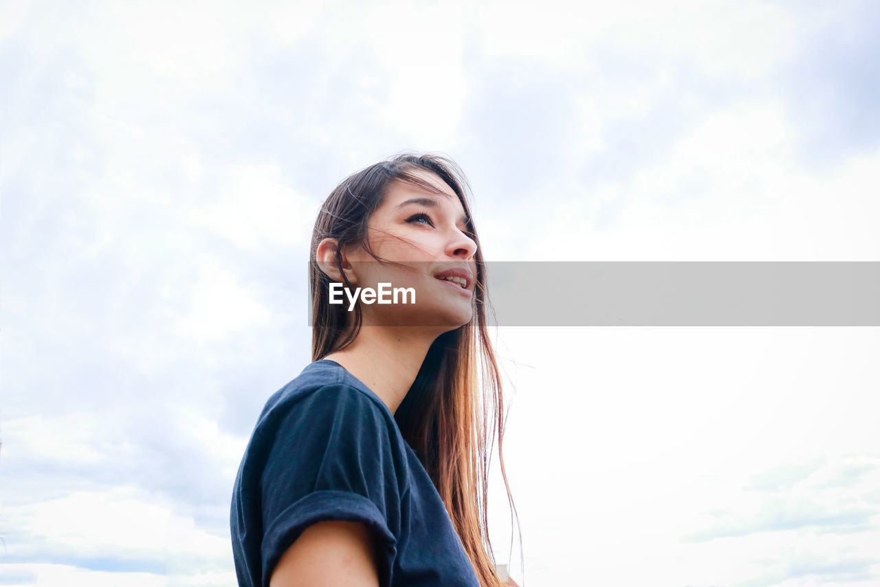 Portrait of smiling young woman against sky