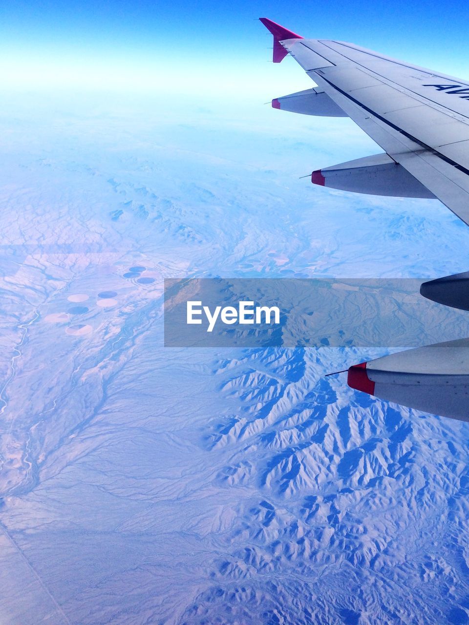 CROPPED IMAGE OF AIRPLANE WING OVER MOUNTAINS