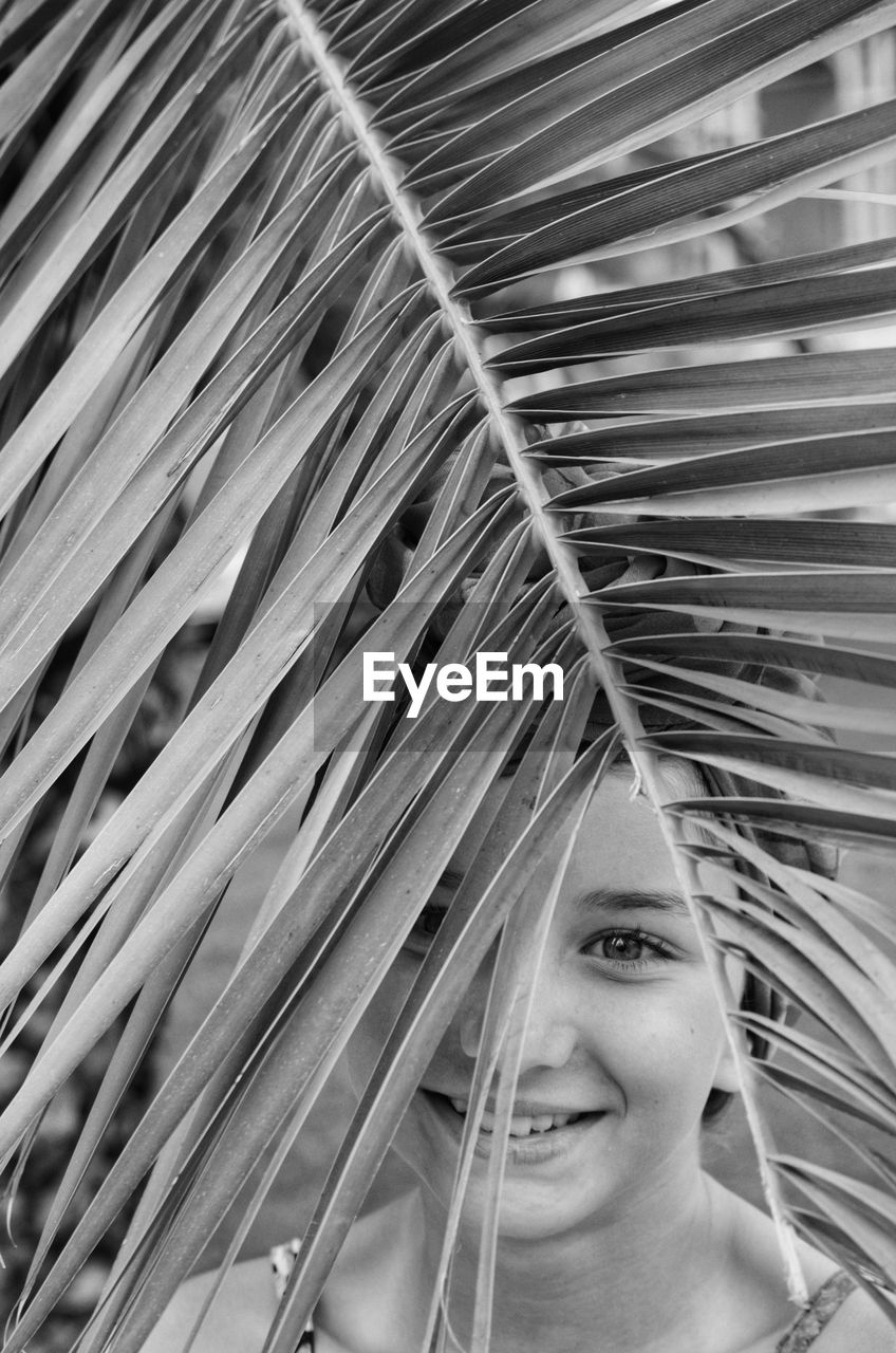 Portrait of smiling teenage girl with palm leaf