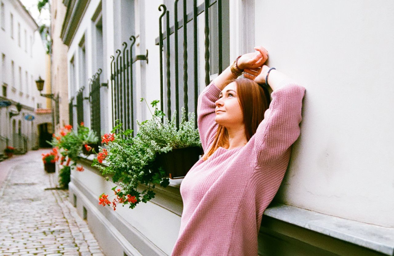 Thoughtful young woman leaning on wall by footpath