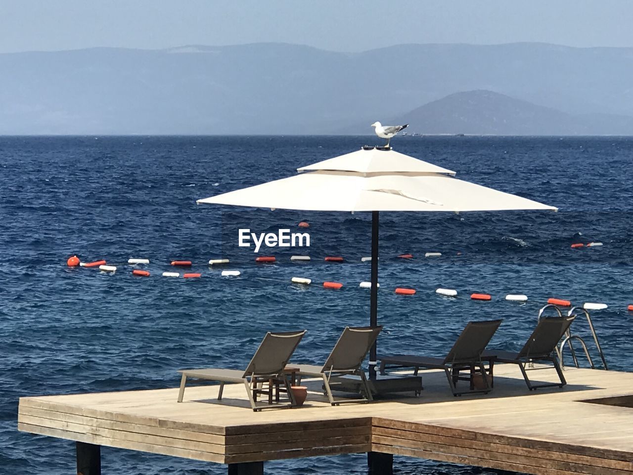 CHAIRS AND TABLE ON SEA AGAINST SKY