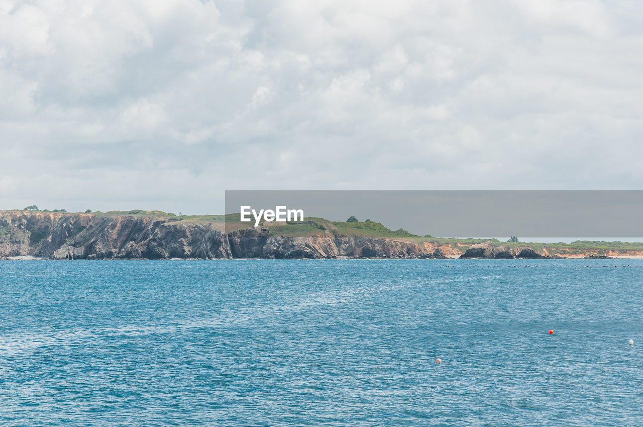 SCENIC VIEW OF SEA BY ROCKS AGAINST SKY