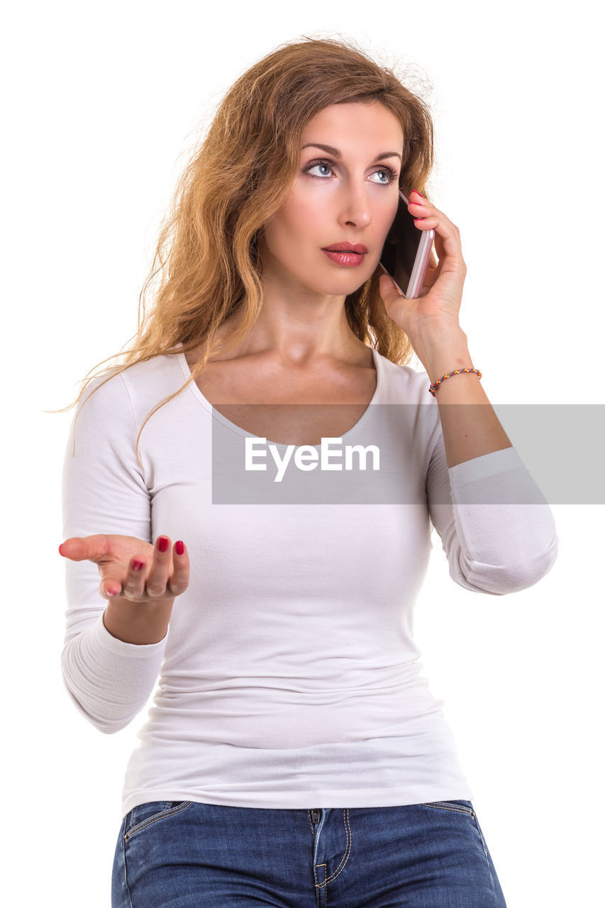 Mid adult woman talking on mobile phone against white background