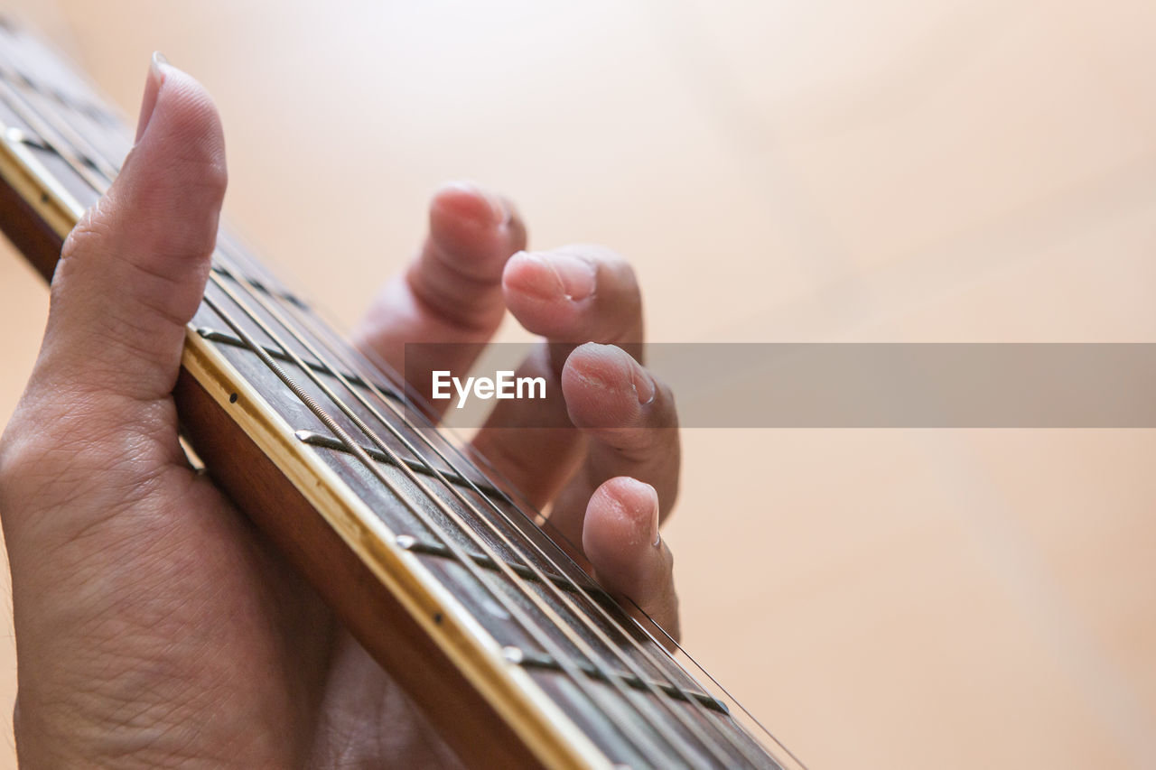 Cropped hand holding guitar fretboard