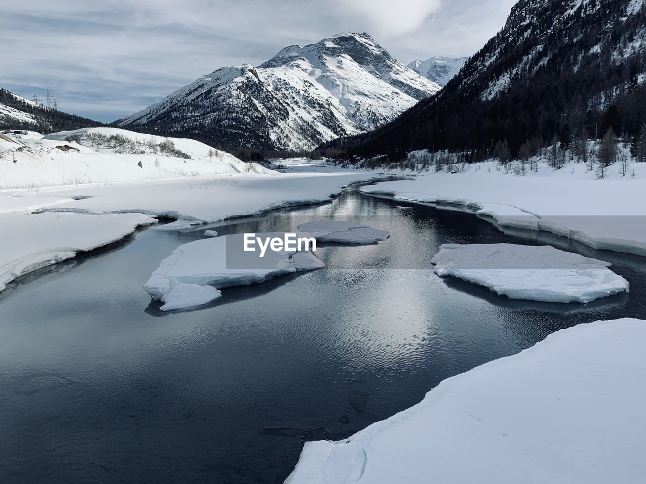 Scenic view of frozen lake by snowcapped mountains against sky