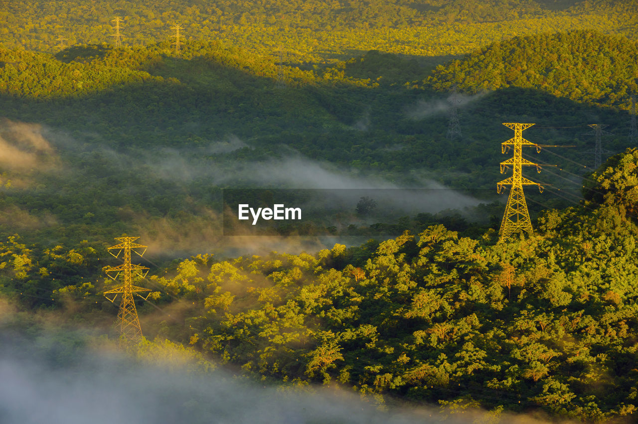 Aerial view transmission tower in green forest and beautiful morning smooth fog. 