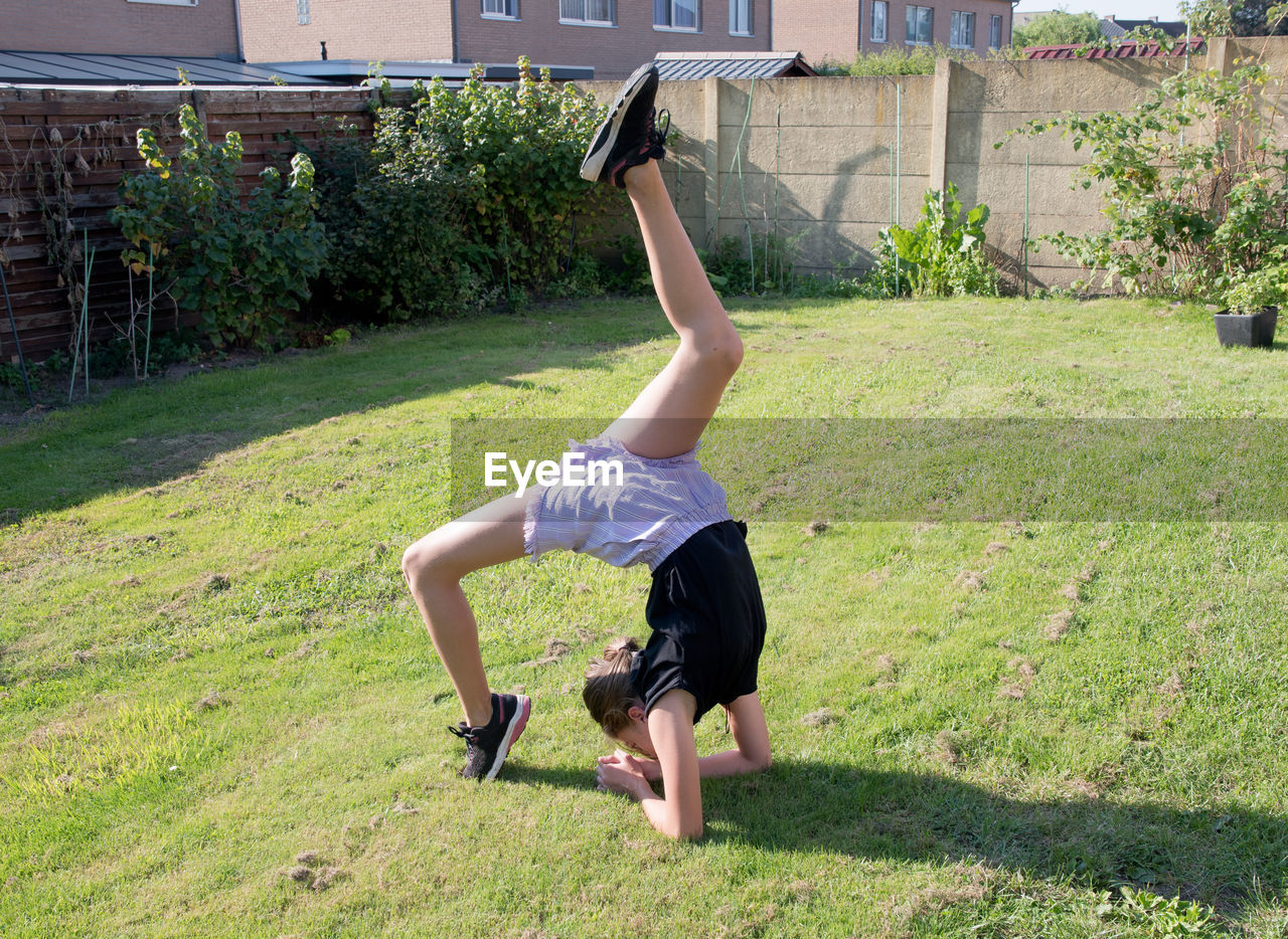 Teenage girl doing acrobatic exercises on a green lawn, sport, generation z,