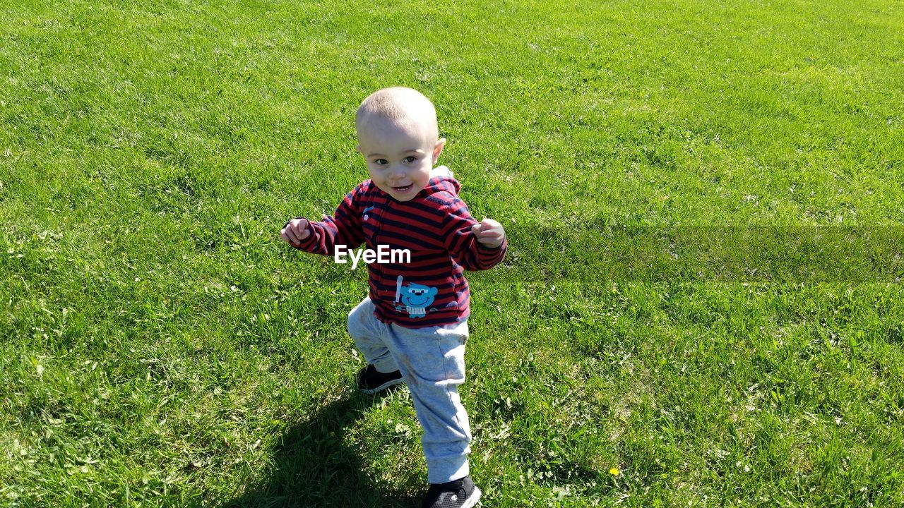 High angle view of playful baby boy gesturing on grass