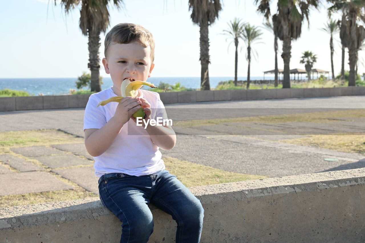 portrait of boy eating food on footpath
