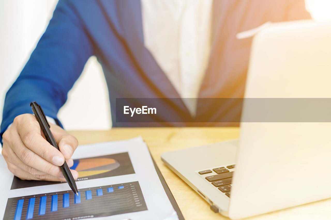 Midsection of businessman working over graph on table