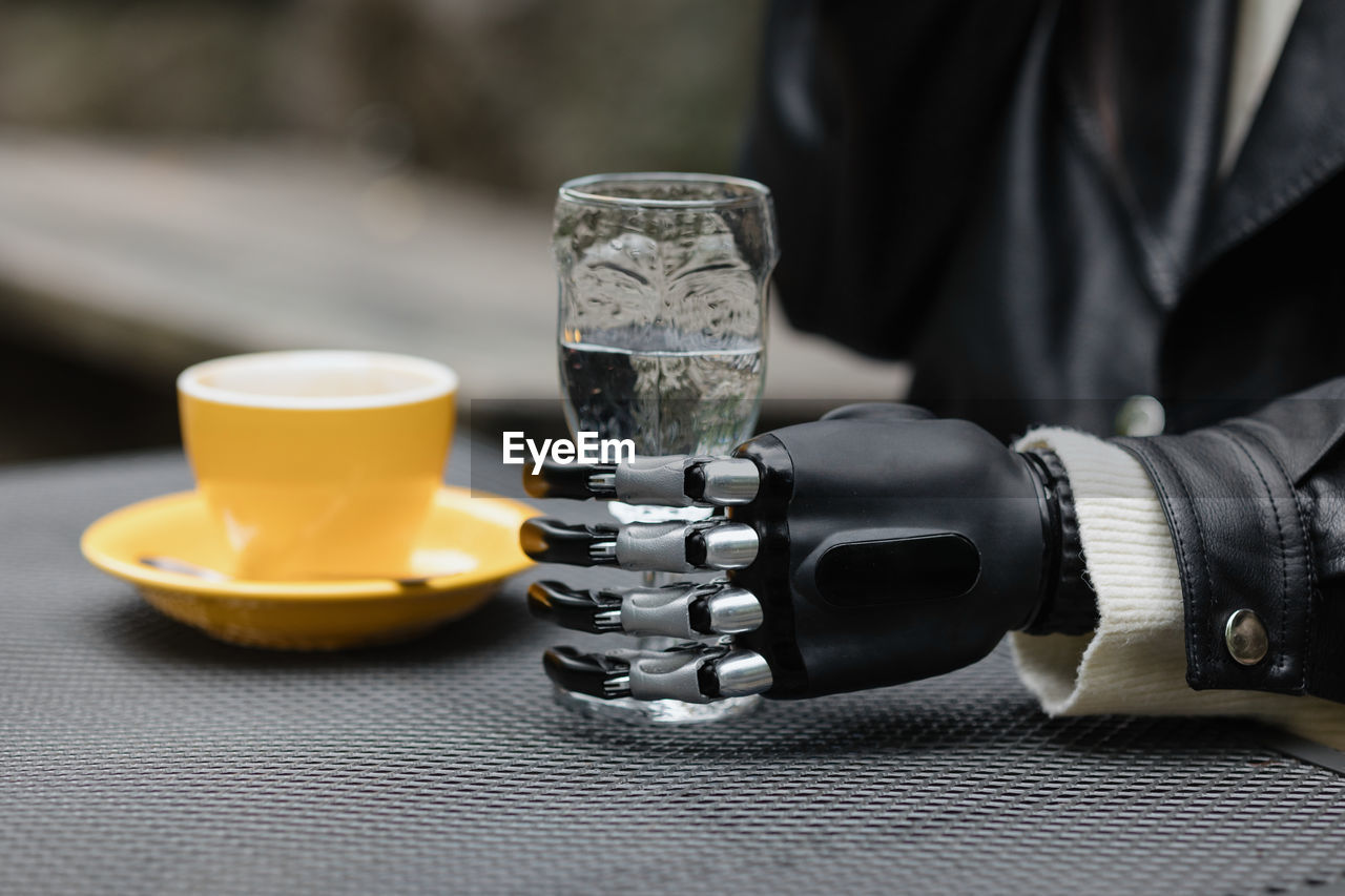 A hand with a bionic prosthesis holds a glass of water. a happy european cyber woman with a bionic