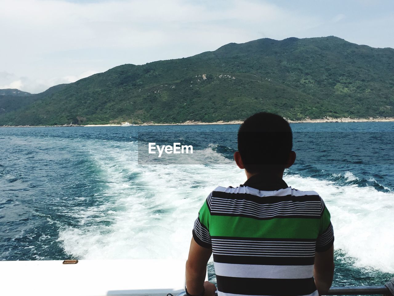 Rear view of man on boat in sea in front of mountain