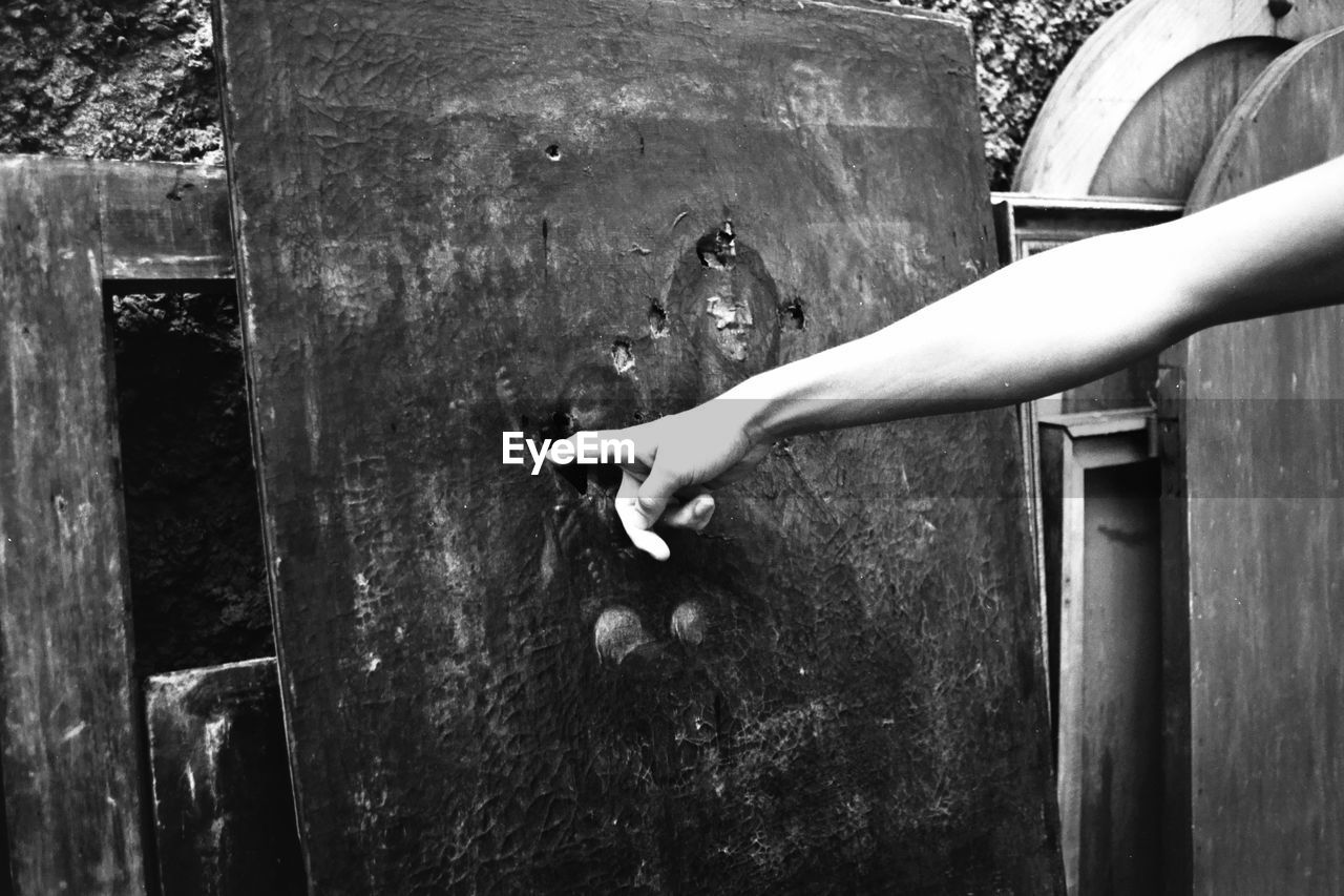 Cropped image of hand touching tombstone