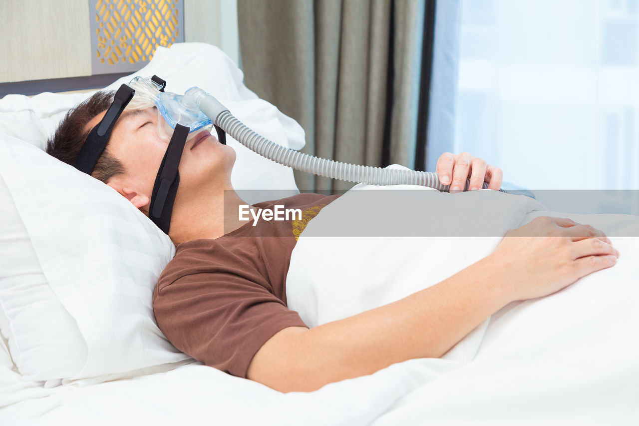 Patient wearing oxygen mask while sleeping on bed in hospital
