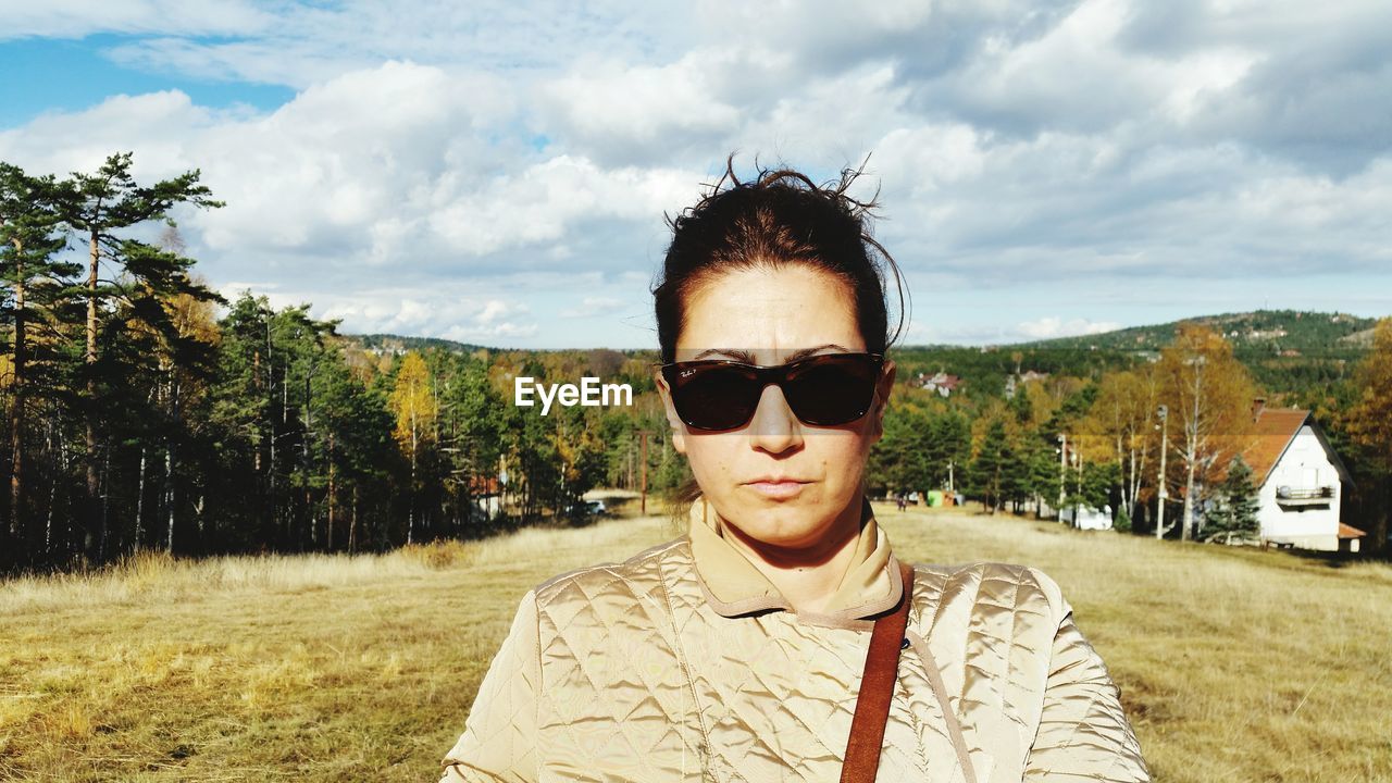 Young woman in sunglasses standing on field