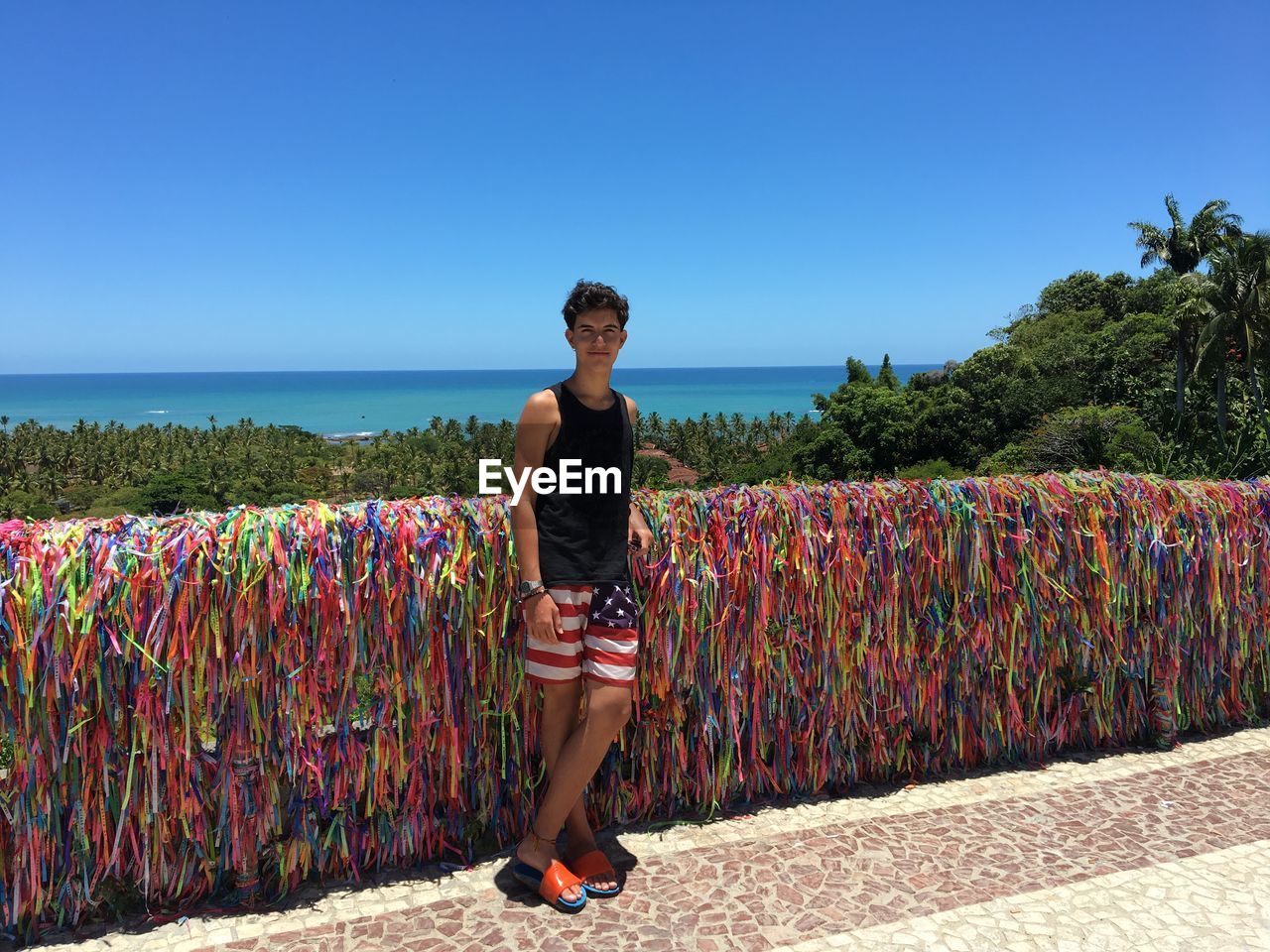 Portrait of boy standing against multi colored ribbons at beach