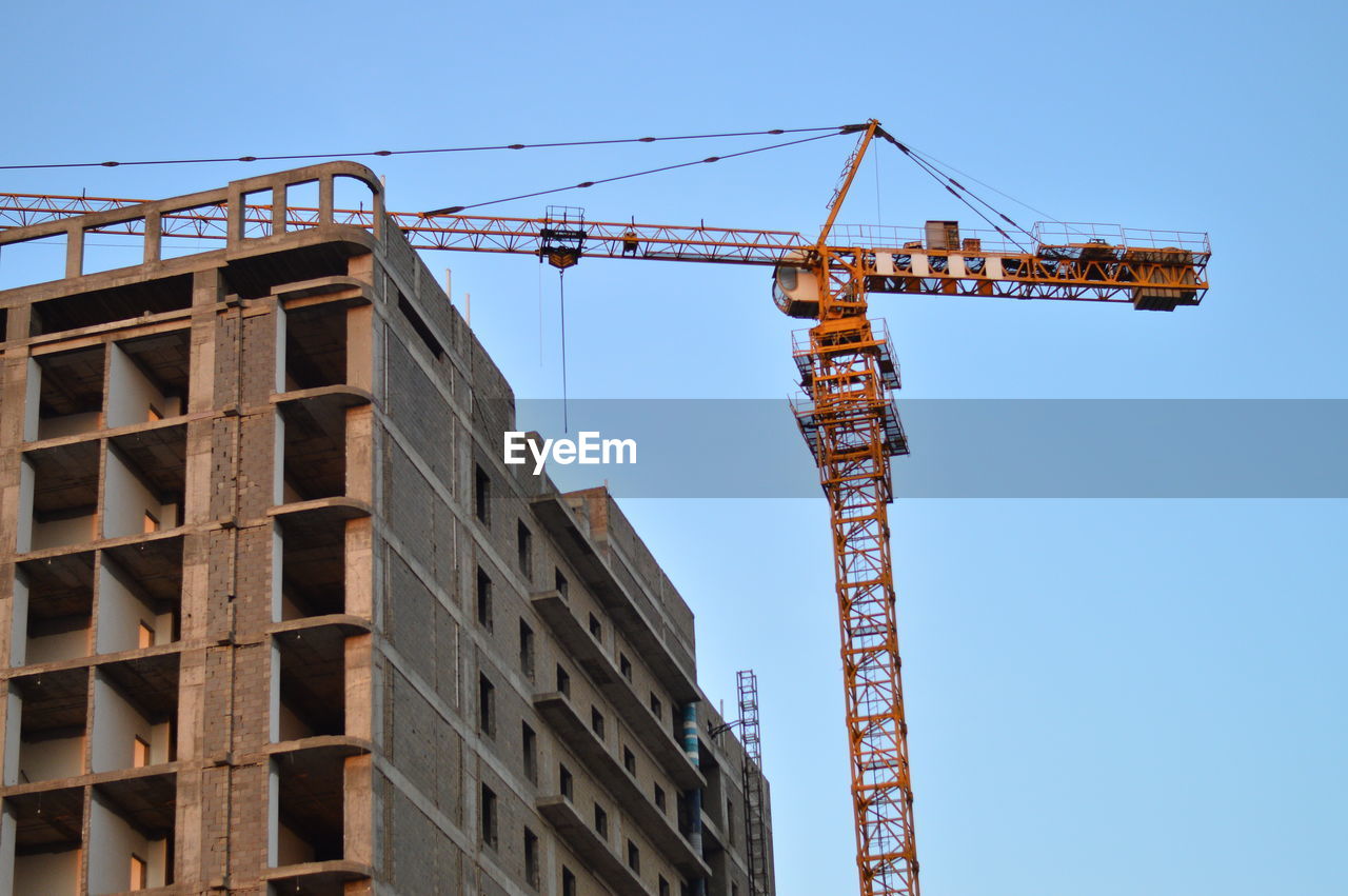LOW ANGLE VIEW OF CRANE AT CONSTRUCTION SITE