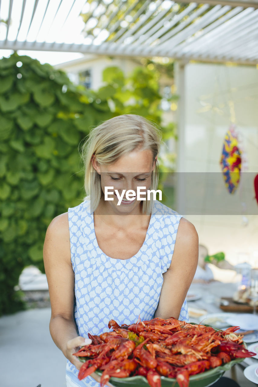 Mature woman holding bowl of crayfish