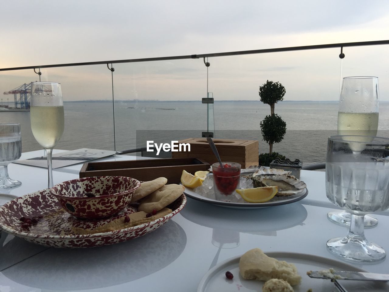 Food with champagne flutes on table at outdoor restaurant by sea