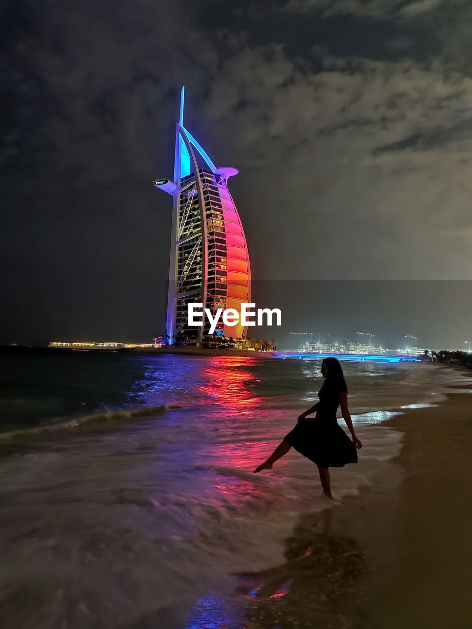 PERSON STANDING ON ILLUMINATED BEACH